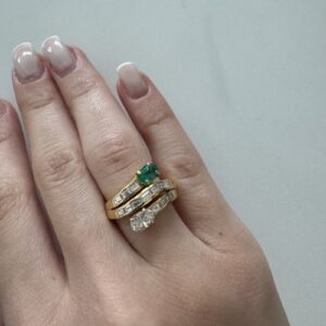 Foto gioiello indossata: anello contrarie in oro giallo con diamanti e smeraldo