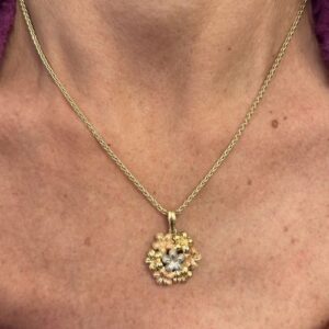 Foto gioiello indossata: collana oro giallo con ciondolo a forma di fiore con lavorazione tre ori