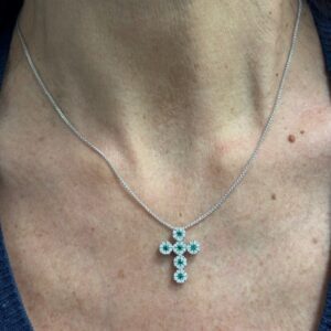 Foto gioiello indossata: collana in oro bianco con ciondolo croce con diamanti e smeraldi
