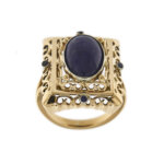 Anello vintage rettangolare con lavorazioni traforate in oro rosa 18 kt con lapislazzuli ovale centrale, taglio cabochon (dimensione 14 x 10 mm) e sui lati 4 piccoli zaffiri da 0.05 ct cad. totale 0.20 ct.