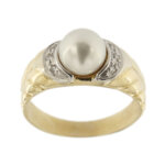 Anello con perla d’acqua salata da 7.5-8 mm, colore bianco, sfumatura grigia in oro giallo e oro bianco 18kt con ai lati 6 diamanti da 0.01 ct cad. totale 0.06 ct - colore FG e purezza VS; gambo decorato a foglie.