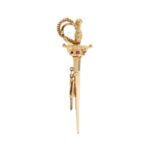 Spilla a forma di spada in oro giallo 18kt arricchita da piccoli rubini, manico intrecciato, lavorazione rilievo con piccole sfere in oro bianco, catenina maglia grumetta fitta e goccia d’oro finale come sicura.