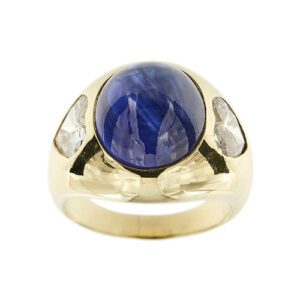 Anello a fascia bombata in oro giallo 18kt con zaffiro ovale cabochon da 12 ct e ai lati 2  diamanti a cuore da 0.95 ct e 0.75 ct - colore FG e purezza VS;Pederzani è una boutique storica di lusso di Milano.