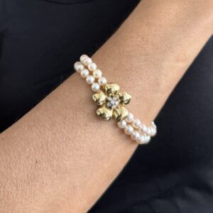 Foto gioiello indossata: bracciale doppio filo di perle con chiusura a forma di fiore con diamanti in oro giallo