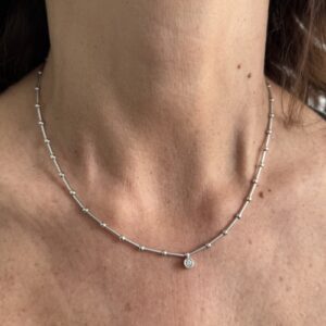 Foto gioiello indossata: collana maglia segmenti con punto luce in oro bianco con diamante